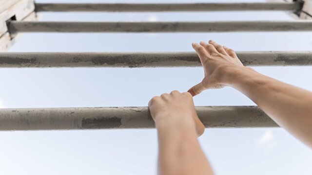 low angle woman climbing metal bars scaled